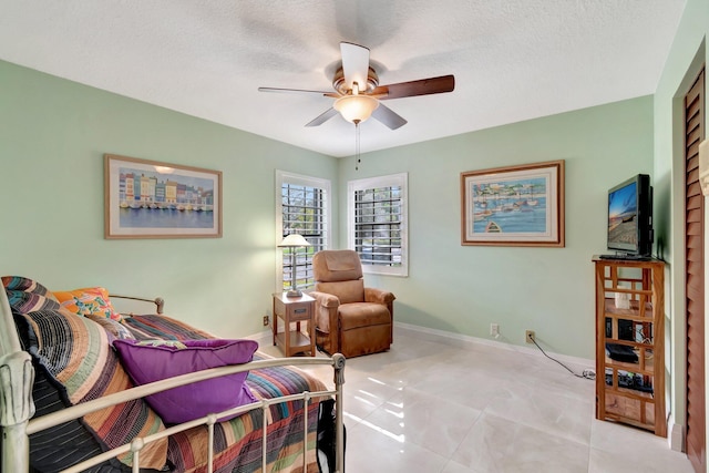 sitting room featuring ceiling fan, light tile patterned floors, and a textured ceiling