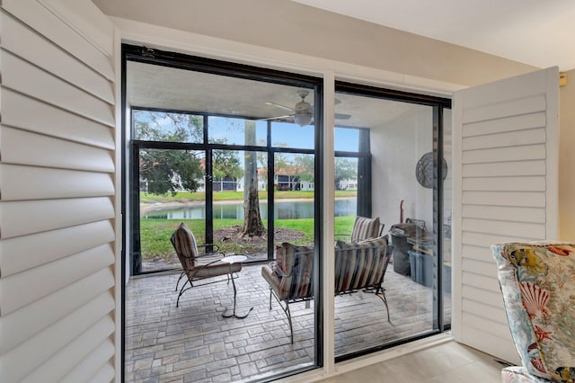 entryway with ceiling fan and a water view