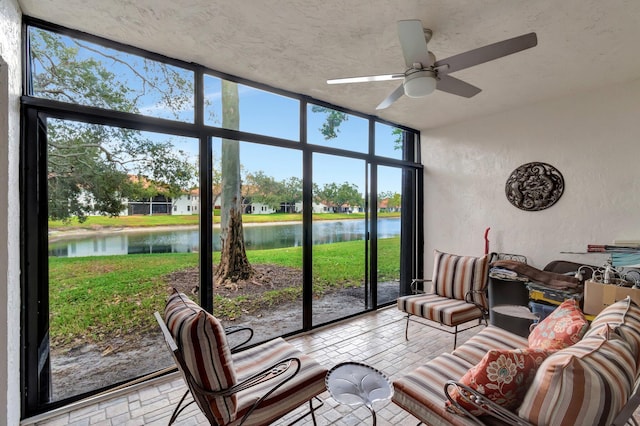 sunroom featuring ceiling fan and a water view