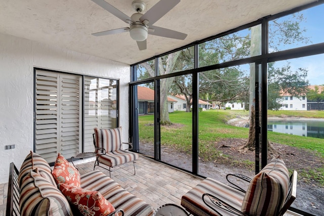 sunroom / solarium with ceiling fan and a water view