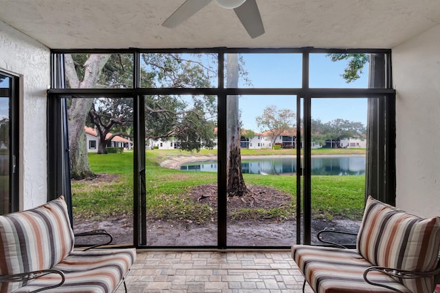 entryway with a wall of windows, a water view, ceiling fan, and a healthy amount of sunlight