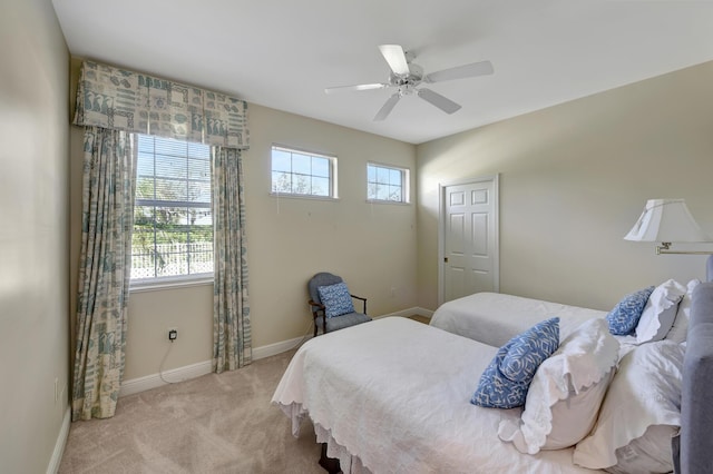 bedroom with multiple windows, ceiling fan, and light carpet