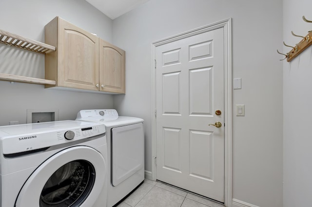 clothes washing area featuring washing machine and dryer, light tile patterned flooring, and cabinets