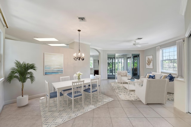 tiled dining space with ceiling fan with notable chandelier and crown molding