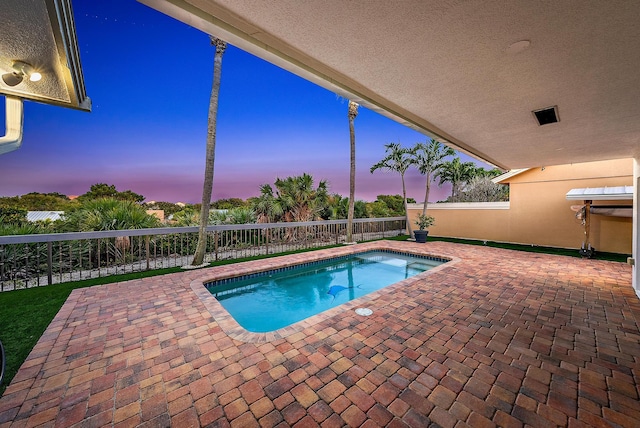 pool at dusk featuring a patio