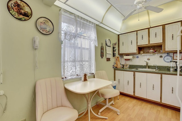 kitchen with decorative backsplash, light hardwood / wood-style floors, ceiling fan, and sink