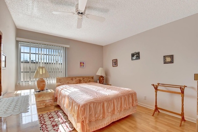 bedroom with ceiling fan, a textured ceiling, and light hardwood / wood-style flooring