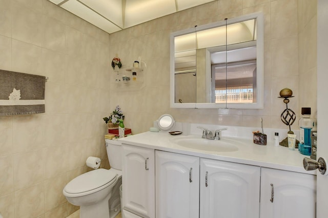 bathroom with vanity, tile walls, and toilet