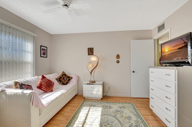 interior space featuring ceiling fan, light wood-type flooring, and a textured ceiling