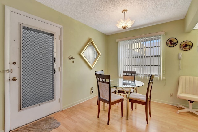 dining area with light hardwood / wood-style flooring, a chandelier, and a textured ceiling