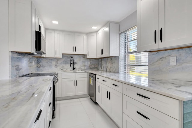 kitchen with sink, stainless steel appliances, light stone counters, backsplash, and white cabinets