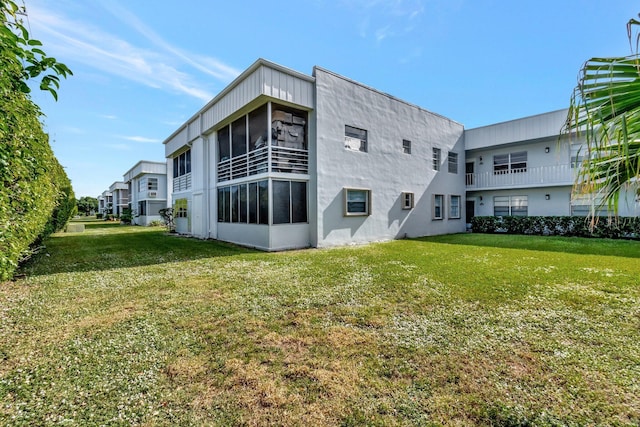 back of property featuring a sunroom and a yard