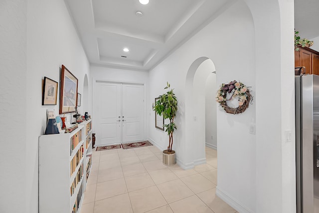 entryway featuring light tile patterned floors and a tray ceiling