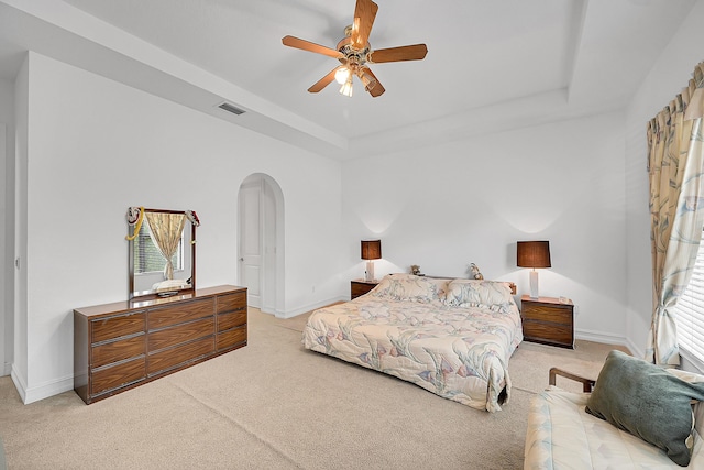 carpeted bedroom with a raised ceiling and ceiling fan