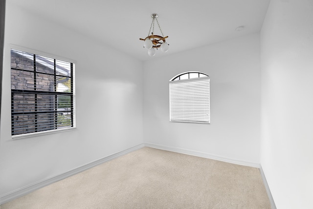 unfurnished room featuring a notable chandelier and carpet floors