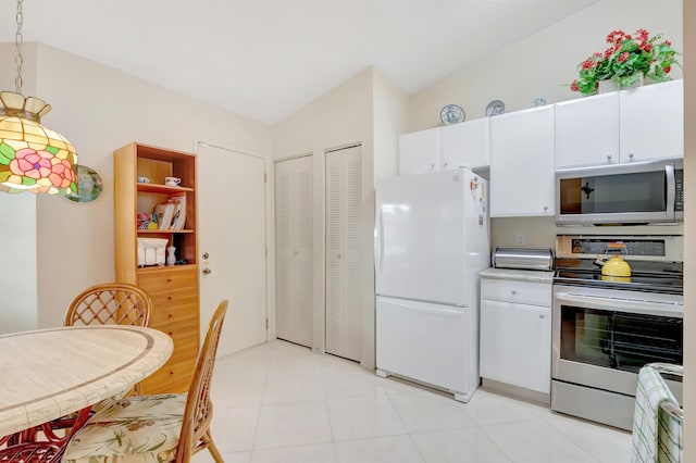 kitchen featuring hanging light fixtures, vaulted ceiling, light tile patterned flooring, white cabinetry, and stainless steel appliances