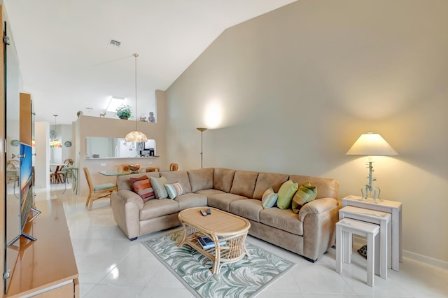 living room with a notable chandelier, lofted ceiling, and light tile patterned flooring