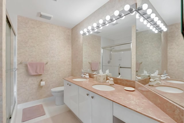 bathroom featuring tile patterned flooring, vanity, a shower with shower door, and toilet