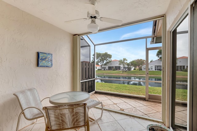 sunroom featuring a water view and ceiling fan