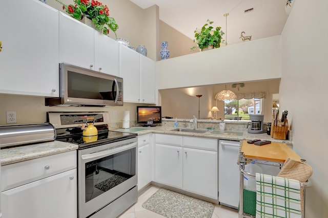 kitchen featuring sink, light tile patterned floors, a towering ceiling, white cabinets, and appliances with stainless steel finishes