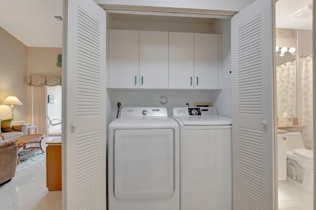 laundry area featuring washer and clothes dryer, light tile patterned floors, and cabinets