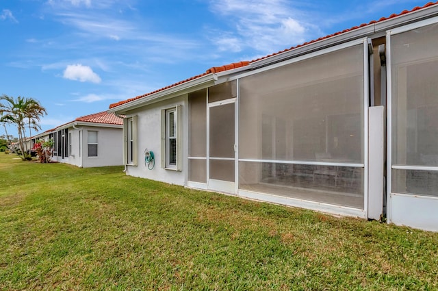 rear view of property featuring a sunroom and a lawn