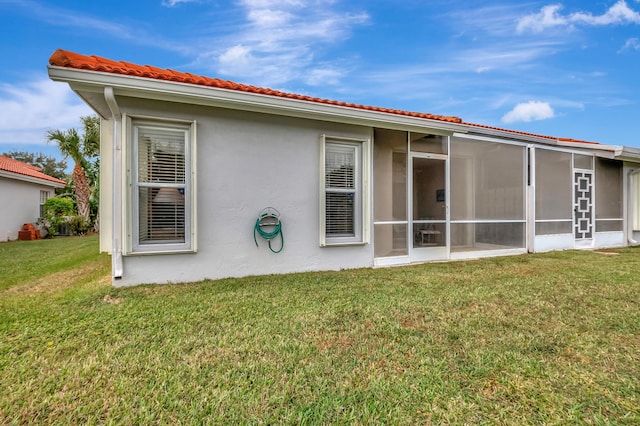 back of house featuring a lawn and a sunroom