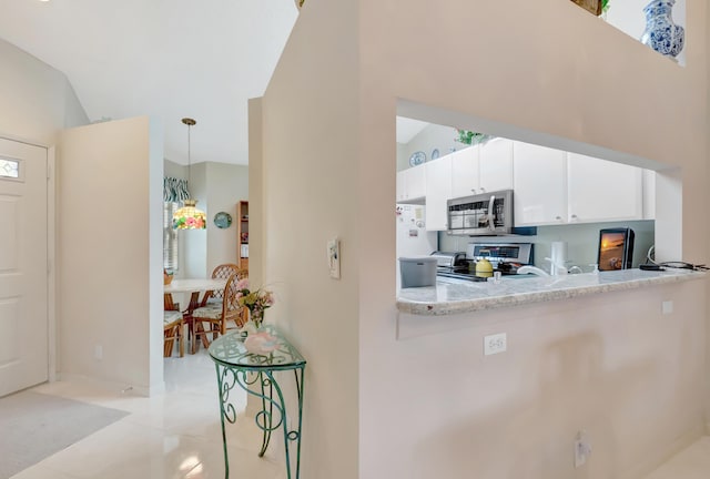 kitchen with white cabinetry, hanging light fixtures, stainless steel appliances, light stone counters, and light tile patterned floors