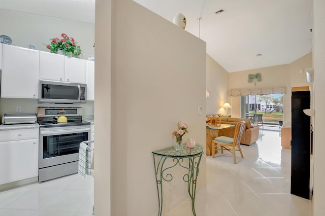 kitchen with white cabinetry, light tile patterned flooring, stainless steel appliances, and lofted ceiling