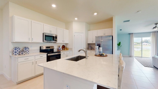 kitchen with white cabinets, a kitchen island with sink, sink, and appliances with stainless steel finishes