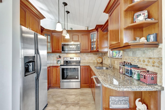 kitchen with appliances with stainless steel finishes, light stone counters, hanging light fixtures, and sink