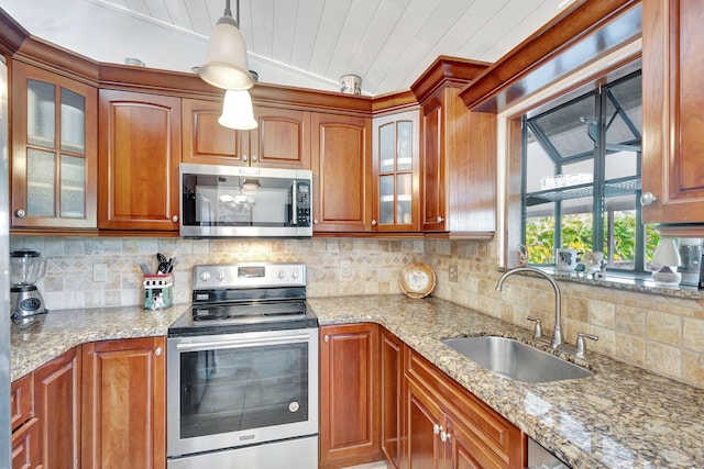 kitchen featuring backsplash, sink, hanging light fixtures, light stone countertops, and stainless steel appliances