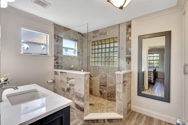 bathroom featuring vanity, a tile shower, and wood-type flooring