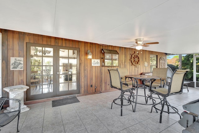 dining area featuring a wealth of natural light, ceiling fan, and wood walls