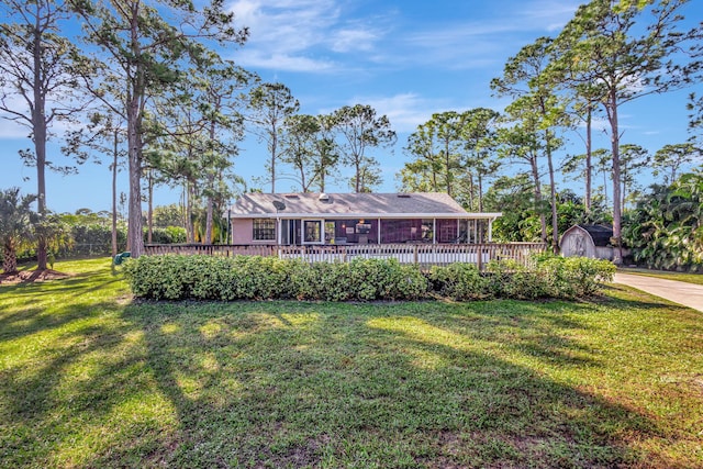 exterior space featuring a storage unit, a front yard, and a wooden deck