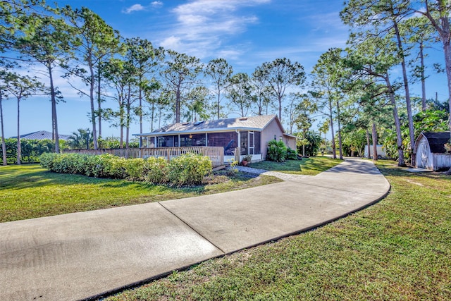 view of front of home with a sunroom, a front yard, and a storage unit