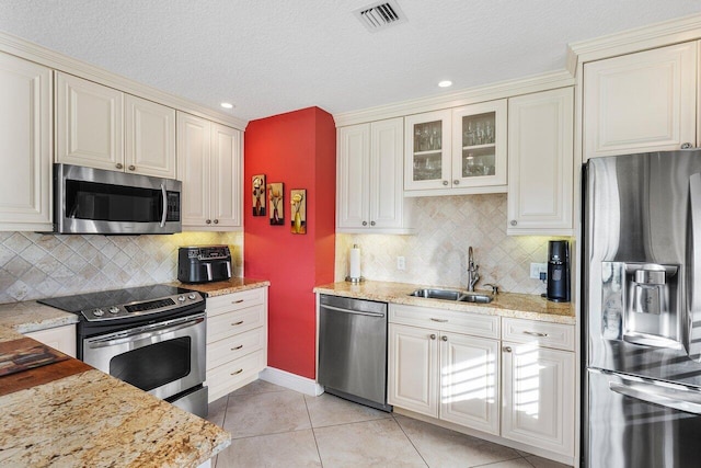 kitchen featuring backsplash, sink, light tile patterned floors, and stainless steel appliances