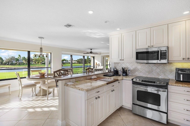 kitchen with a water view, ornamental molding, appliances with stainless steel finishes, light tile patterned flooring, and kitchen peninsula