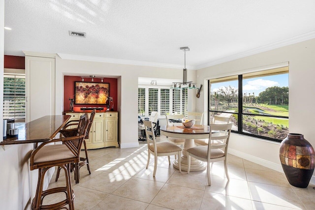 tiled dining room featuring a textured ceiling and ornamental molding