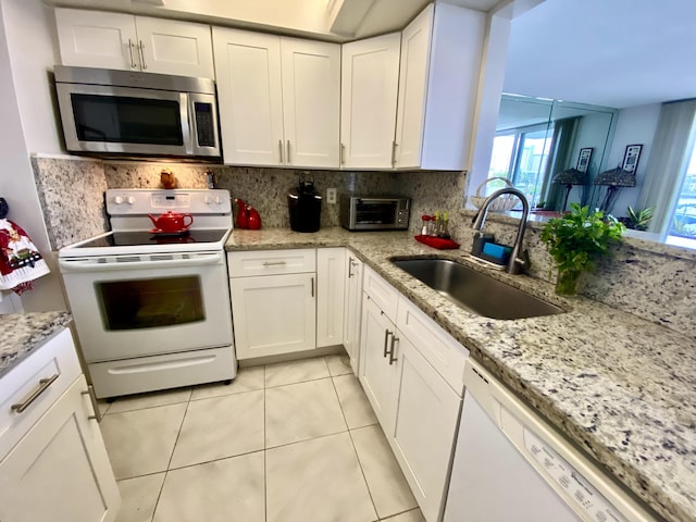 kitchen with decorative backsplash, white cabinetry, white appliances, and sink