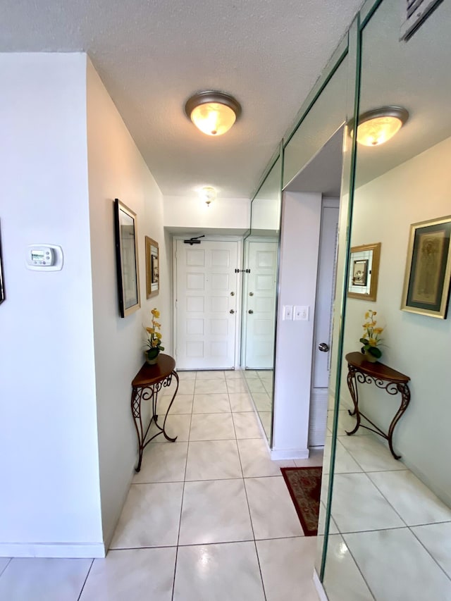 hallway featuring light tile patterned floors and a textured ceiling