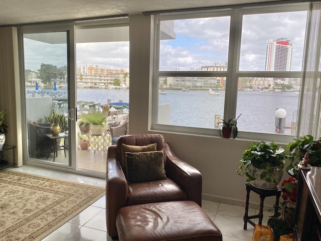 sitting room with light tile patterned flooring, a water view, and a textured ceiling