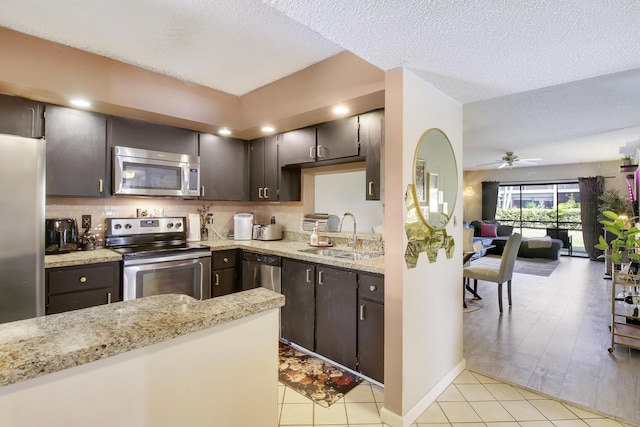 kitchen with appliances with stainless steel finishes, dark brown cabinets, ceiling fan, sink, and light hardwood / wood-style floors