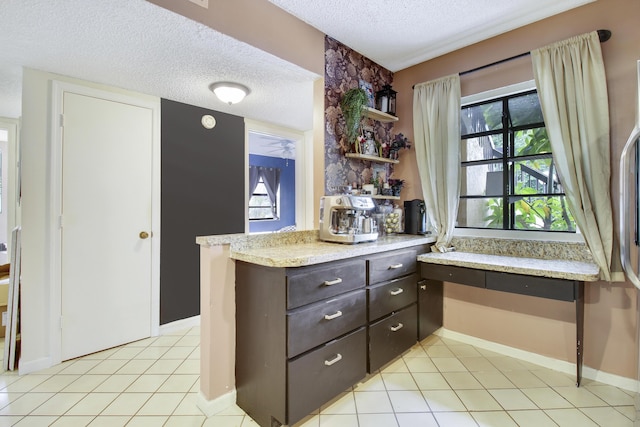 kitchen featuring dark brown cabinets, light tile patterned floors, built in desk, and a textured ceiling