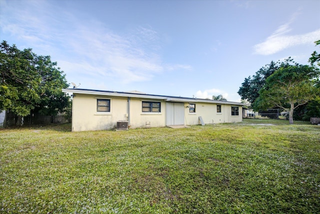 rear view of house with central AC and a yard