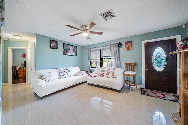 tiled living room featuring ceiling fan and a textured ceiling