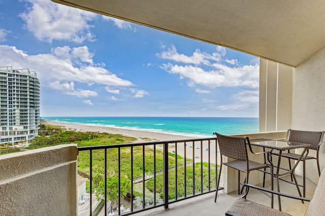 balcony with a water view and a view of the beach