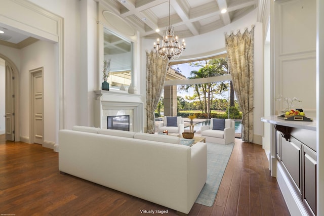 living room with ornamental molding, coffered ceiling, beam ceiling, a notable chandelier, and a high ceiling