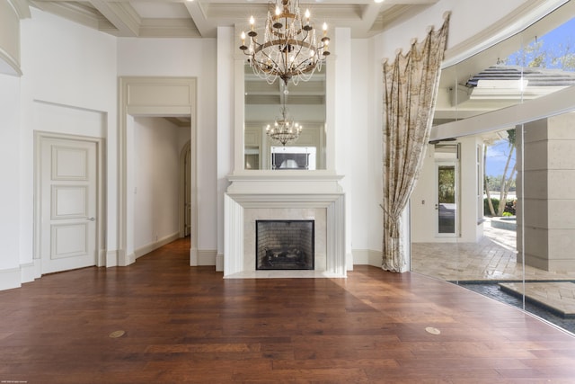 unfurnished living room featuring dark wood-type flooring, coffered ceiling, a premium fireplace, a notable chandelier, and beam ceiling