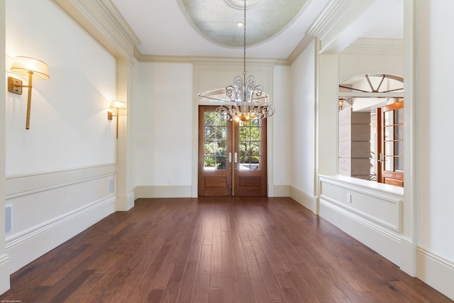 entrance foyer with french doors, a raised ceiling, ornamental molding, dark hardwood / wood-style flooring, and a chandelier